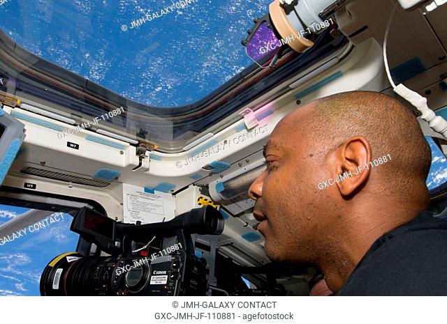 Astronaut Robert L. Satcher Jr., STS-129 mission specialist, uses a High Definition Video (HDV) camera at a window on the aft flight deck of Space Shuttle...