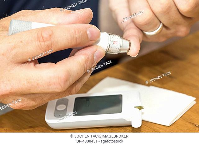 Diabetics taking a blood glucose test, with a lancing device a drop of blood is produced at the fingertip, Germany
