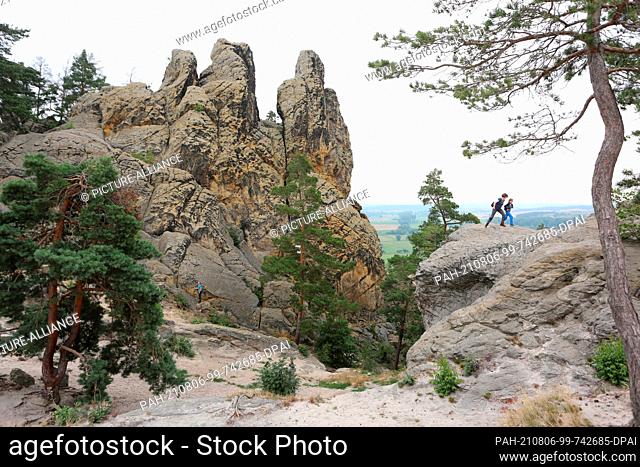 05 August 2021, Saxony-Anhalt, Timmenrode: Hikers take the path leading over the Teufelsmauer to Blankenburg to the rock formation ""Drei Zinnen""