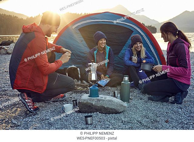 Group of hikers camping at lakeshore at sunset