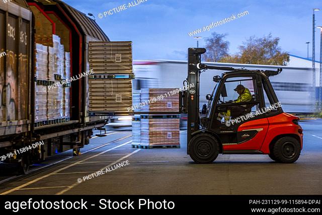 PRODUCTION - 21 November 2023, Mecklenburg-Western Pomerania, Rostock: Pallets and transported goods are reloaded into wagons by trailers of the logistics...