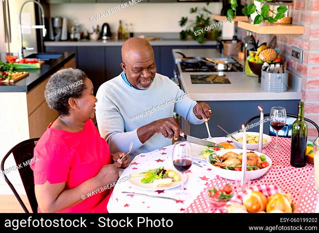Happy african american senior couple eating christmas meal at home