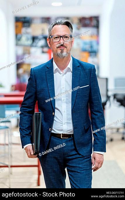 Mature male entrepreneur standing with file at office