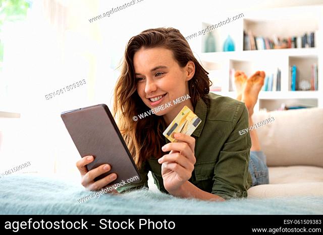 Woman with credit card using digital tablet at home
