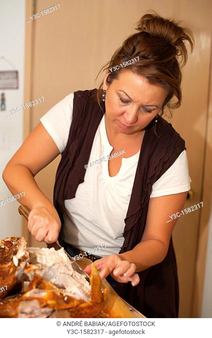 Woman is cutting meat off a turkey roast