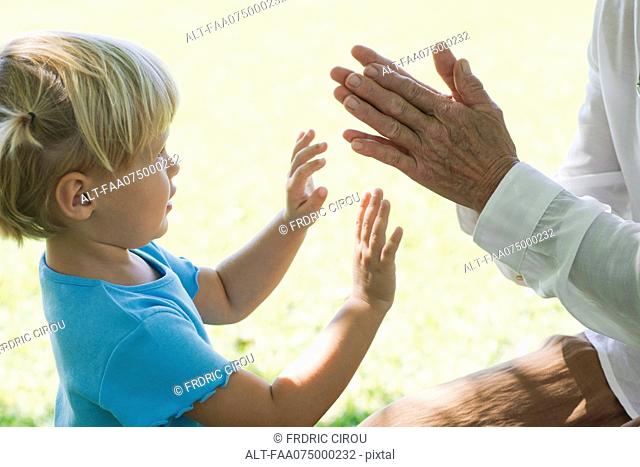 Little girl playing clapping game with grandmother, cropped