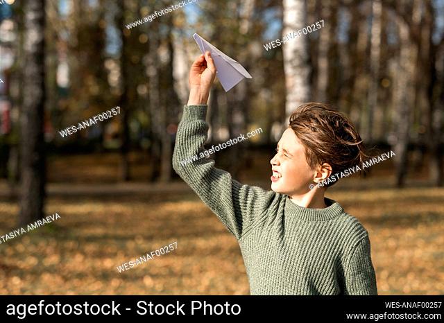 Boy playing with paper airplane in park