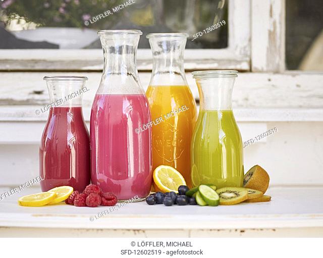 Various smoothies in glass bottles on a window sill