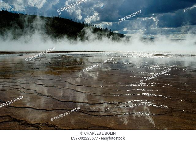 Grand Prismatic Spring, a forested ridge and low clouds, Yellowstone National Park, Wyoming, USA