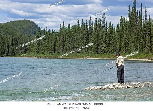Man fishing on gravel bar, upper Liard River, Yukon Territory, Canada