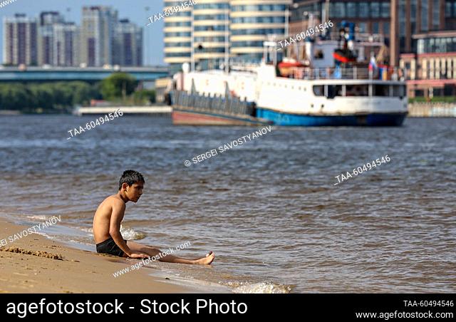 RUSSIA, MOSCOW - JULY 16, 2023: A boy sits by the Moscow Canal near Severnoye Tushino Park. Sergei Savostyanov/TASS