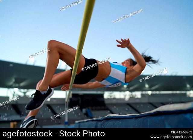 Female track and field athlete high jumping over pole