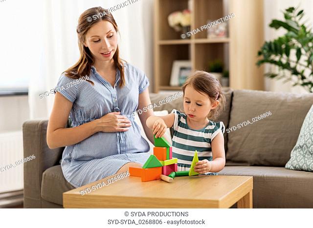 pregnant mother and daughter with toy blocks