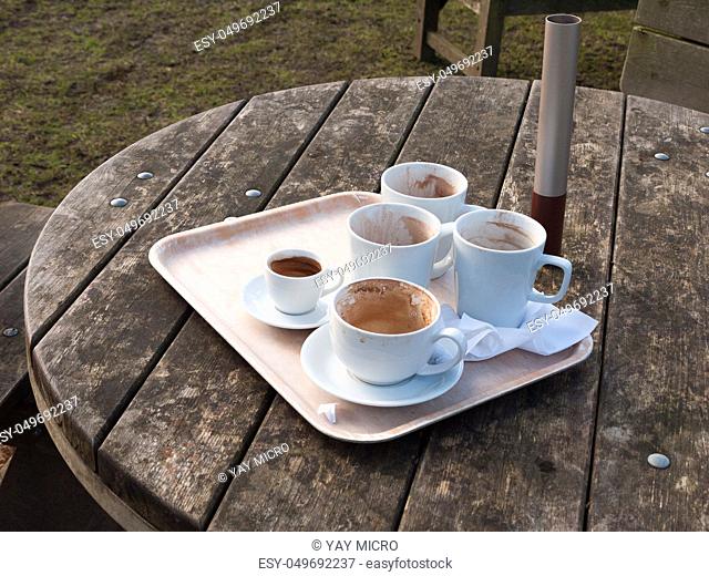 used white cups on tray on wooden table outside cafe close up; essex; england; uk