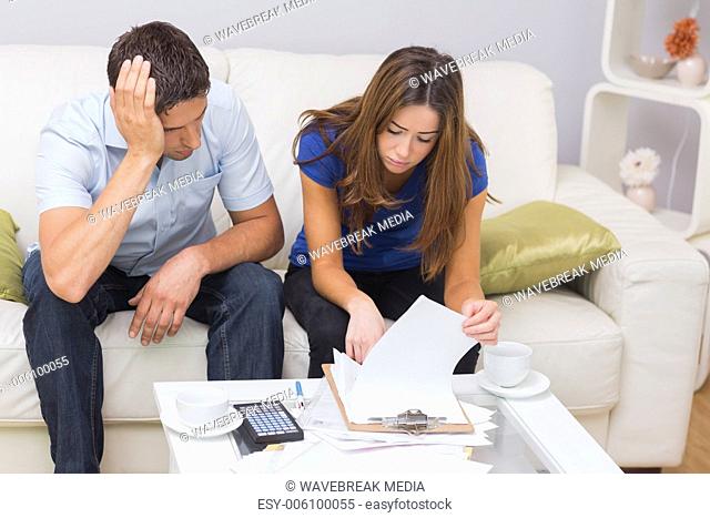 Worried couple paying their bills in living room at home