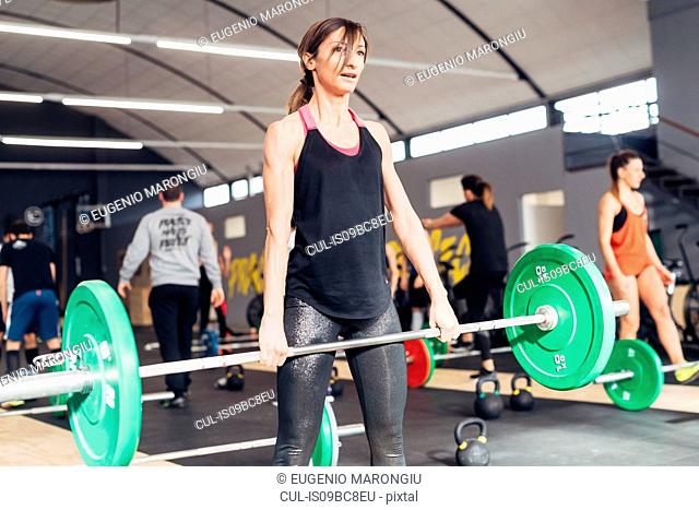 Young woman weightlifting with barbell in gym