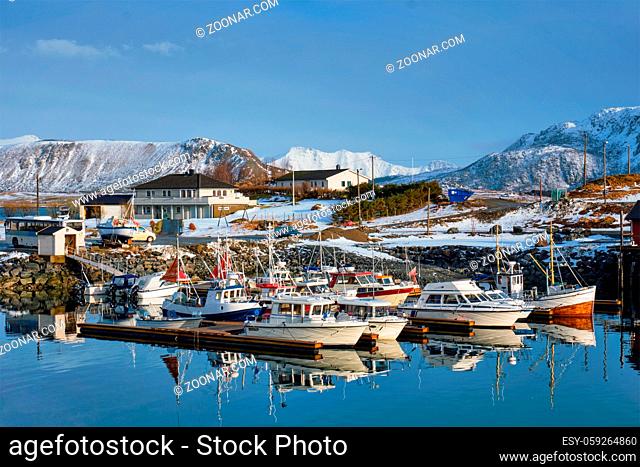 Fishing boats and yachts on pier in Norwegian fjord in village on Lofoten islands in winter, Norway