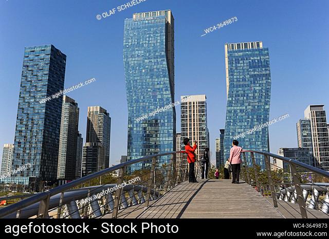 Seoul, South Korea, Asia - People on a bridge in front of the cityscape of New Songdo City in Central Park and the international business district (SIBD) with...