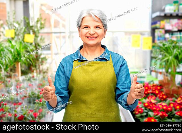 senior woman showing thumbs up in gardening center