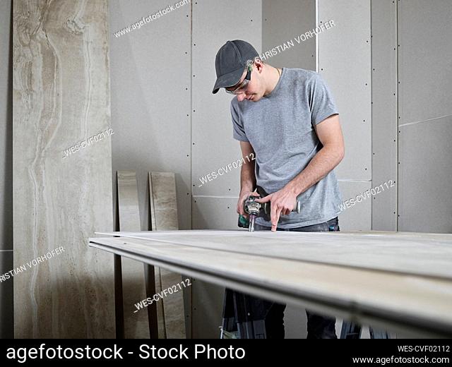 Tiler using drill on tile at construction site