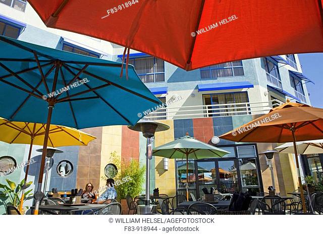 USA, California, Alameda County, Oakland, Jack London Square, outdoor restaurant with umbrellas, diners, hotel, overlooking Oakland Inner Harbor waterway, NR