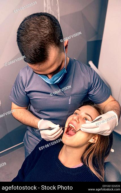Patient at dentist office. Young woman sitting at the chair in dental office and doctor examining teeth