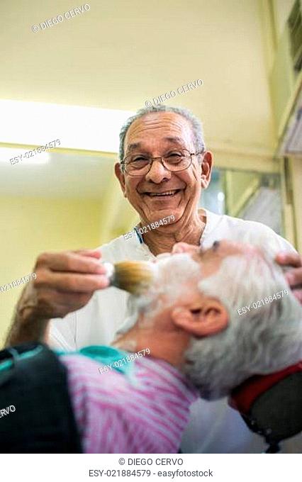 Senior man at work as barber shaving customer