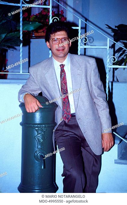 Italian TV host Fabrizio Frizzi leaning against a drinking fountain in the studios of the TV show I fatti vostri. 1990
