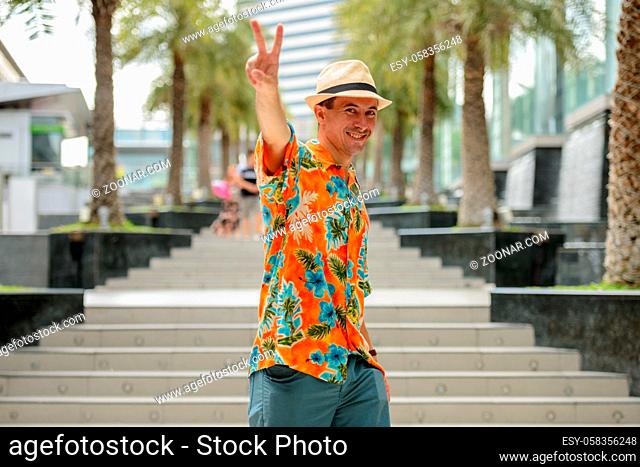 Portrait of young handsome tourist man outside shopping mall in the city