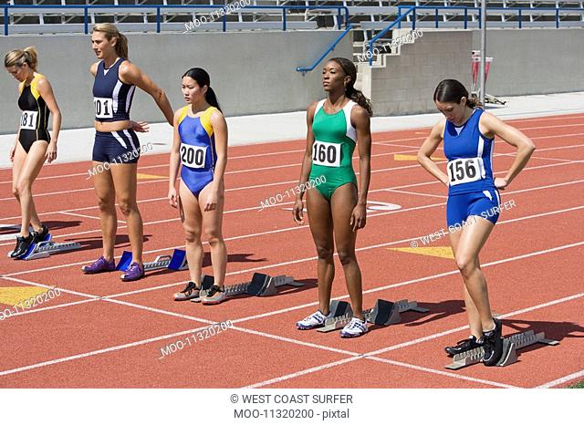 Female athletes next to starting blocks ready to run