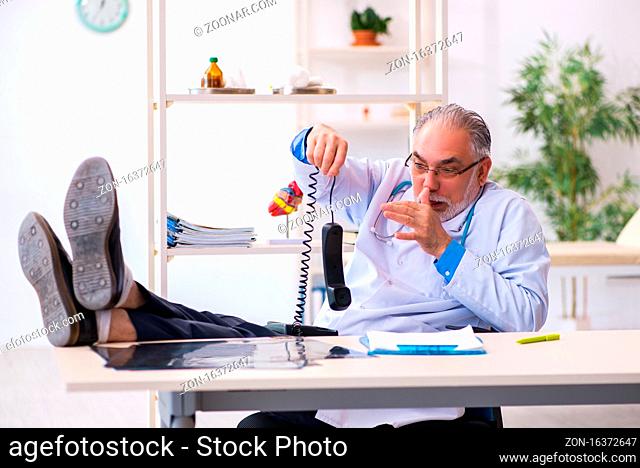 Senior male doctor talking by telephone in the clinic