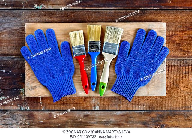 Concept: home repair, house building. Gloves and brushes on old wooden boards