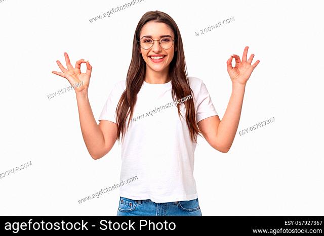 Waist-up portrait of smiling happy attractive girl in glasses and t-shirt, showing okay signs in approval, give positive reply, recommend or review good product