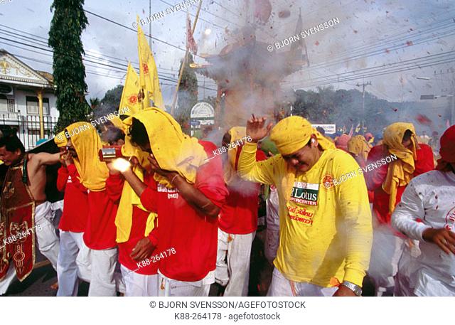 Firecrackers are thrown at religious procession to scare away evil spirits. Vegetarian Festival. Phuket. South Tahiland
