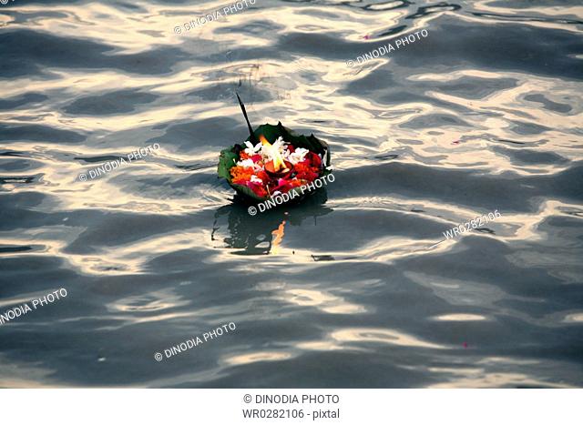 Holy offering of flowers with agarbatti and diya in Ganga river , Rishikesh , Uttaranchal , India