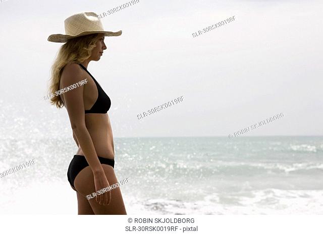 Girl with straw hat. ocean behind her