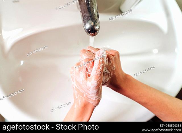 Man washing hands in modern sink with soap and lathering suds to protect against the coronavirus