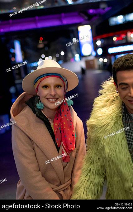 Portrait happy stylish couple on city street at night