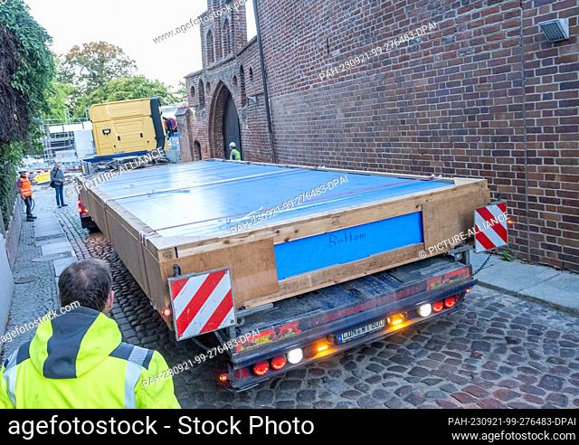 21 September 2023, Mecklenburg-Western Pomerania, Stralsund: A truck maneuvers a pane weighing several tons to the construction site in Stralsund's medieval old...