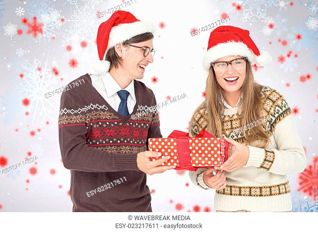 Composite image of geeky hipster couple holding present