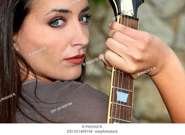 Woman holding her electric guitar behind her back