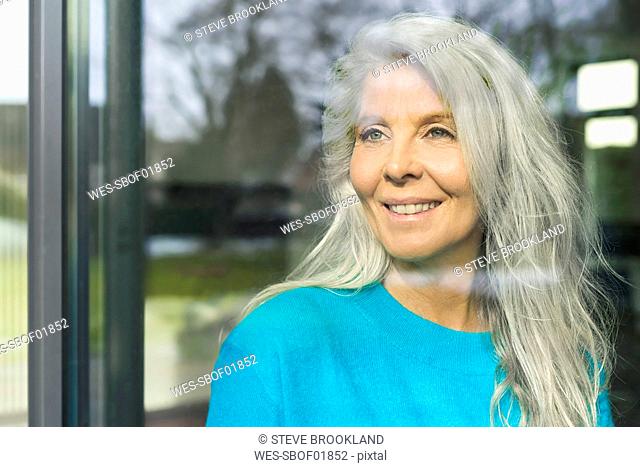 Portrait of happy mature woman looking out of window