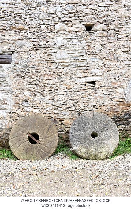Old millstones against a stone wall. Agorregi, Pagoeta Natural Park, Guipuzcoa, Spain