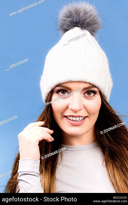 Attractive woman in winter cap and gray sports thermolinen underwear for skiing training studio shot on blue. Long sleeves top
