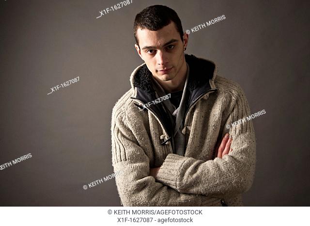 A slim thin slender late teen boy young man adult, with his arms folded UK