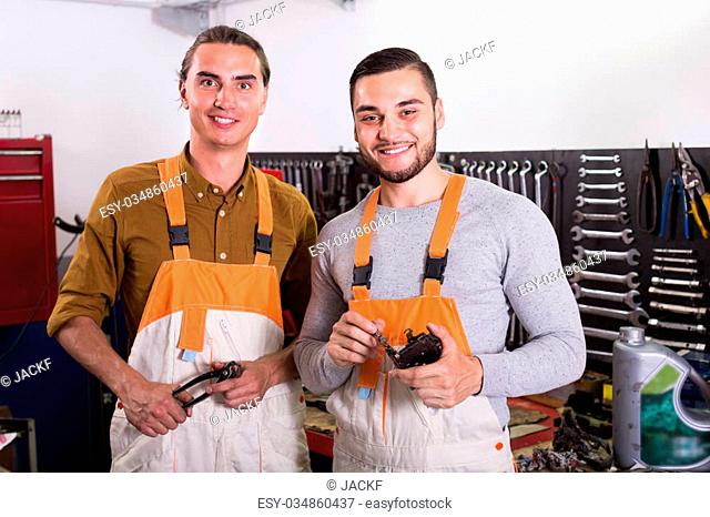 Portrait of two joyful smiling workers in workwear at workshop. Selective focus