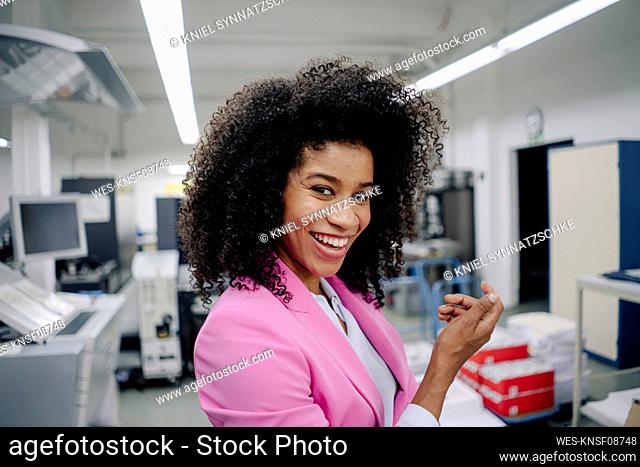 Happy Afro businesswoman standing in industry