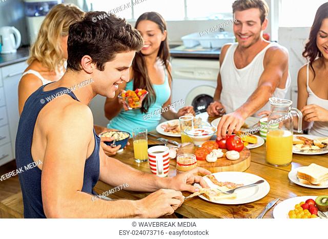 Young man having breakfast with friends at home