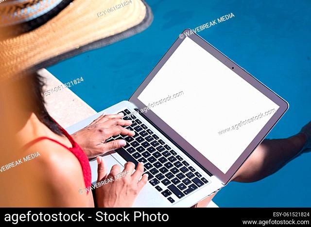 Mixed race woman at home using laptop by the pool