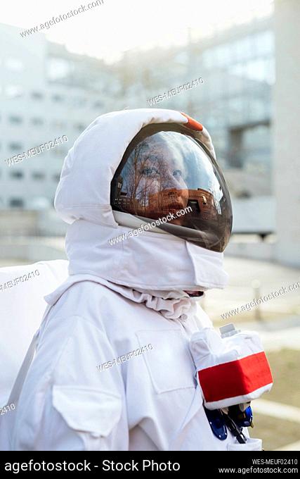 Female astronaut in space suit looking away in city
